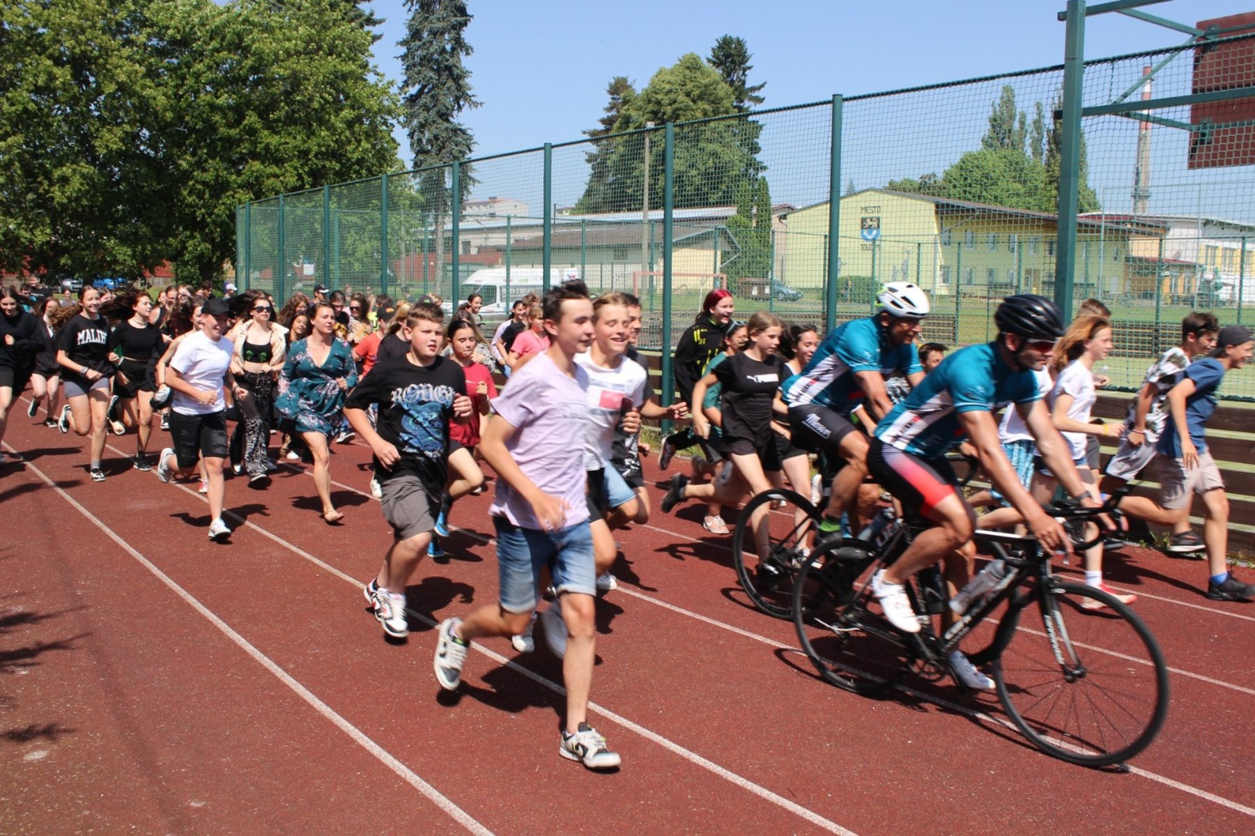 Místní školáci běží s cyklisty, když míří do dalšího místa na jejich cestě po 41 městěch v České republice v roce 2023